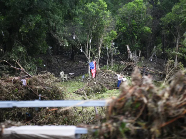 An American flag hangs over wreckage from the July 2025 floods in Texas